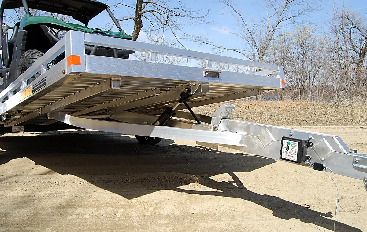 A hydraulic tilt bed trailer lowered to the ground for drive-on loading, representative of the model in the fleet